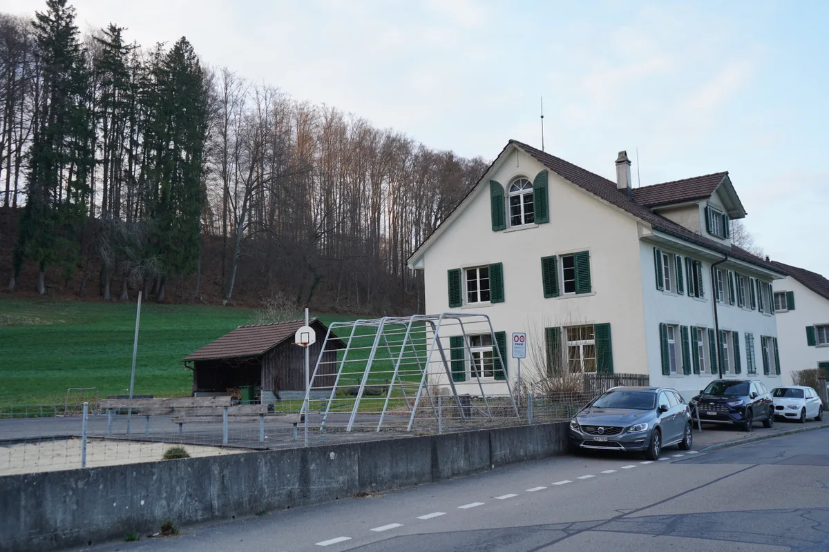 Das alte Schulhaus in Neschwil mit Kinderspielplatz und Klettergerüst.
